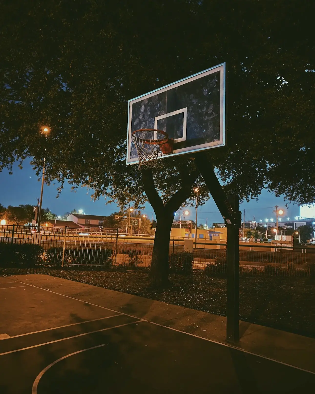 An outdoor basketball hoop under the evening sky